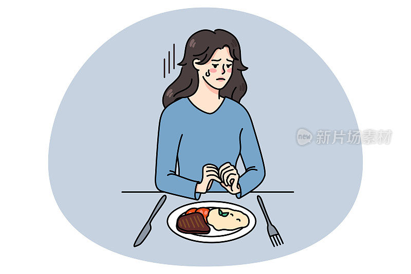 不开心的女人坐在盘子旁，患了饮食失调症