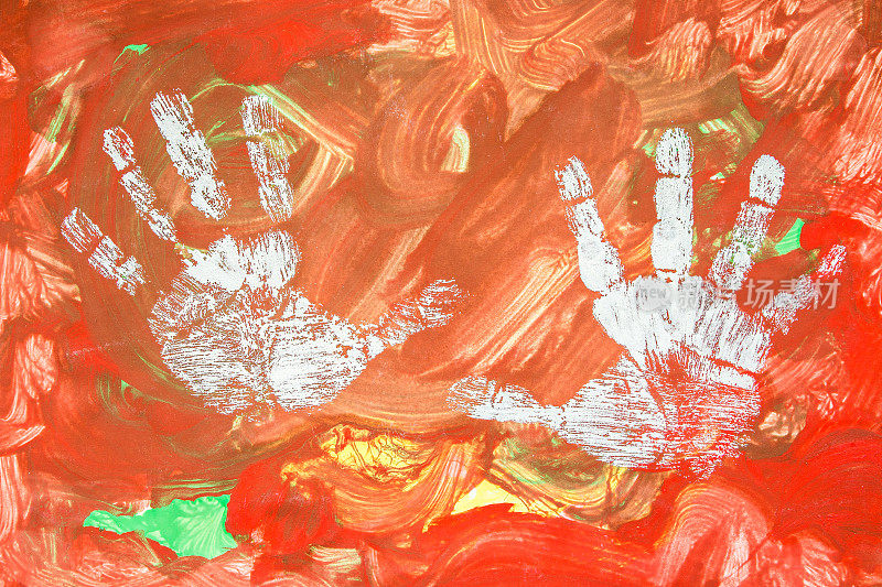 孩子用他白皙的双手在彩色的背景上作画