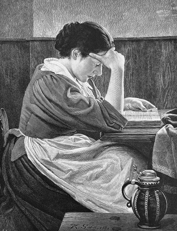 一个年轻的女人坐在桌子旁研究一本书，她的手放在额头上