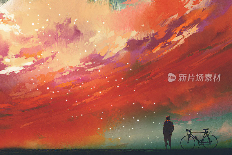 一个骑着自行车的人站在天空的红云下