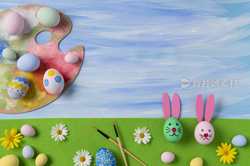 用复活节兔子刷子和蓝色水彩调色板画复活节彩蛋