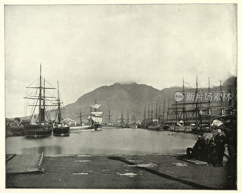 19世纪的维多利亚时代，南非开普敦的海港，码头旁停泊着帆船