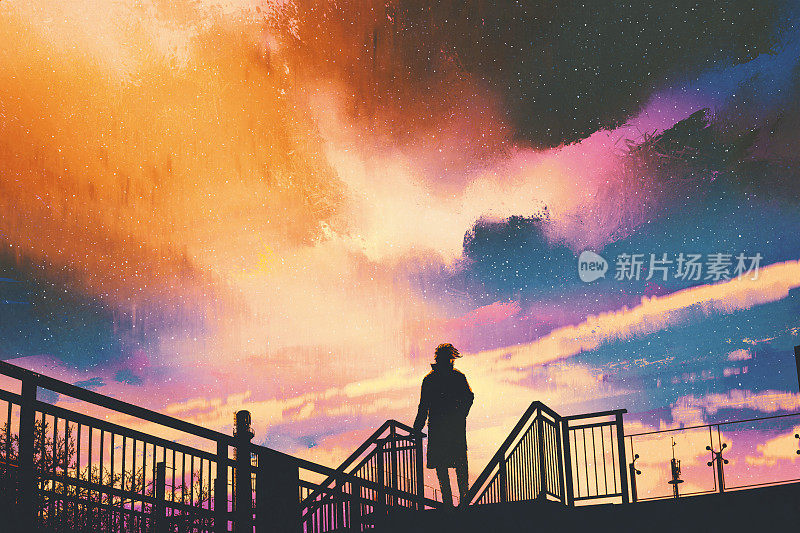 一个人的剪影站在人行桥上，映衬着缤纷的天空