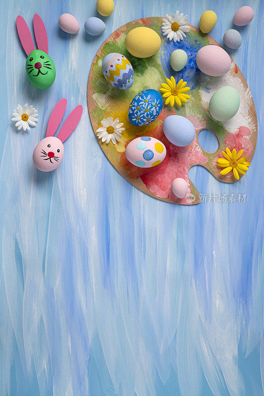 在蓝色水彩上用复活节兔子刷子和调色板画复活节彩蛋