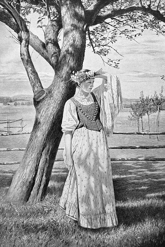 年轻的春美人站在一棵树前，捧着一束鲜花，手臂举在额头上