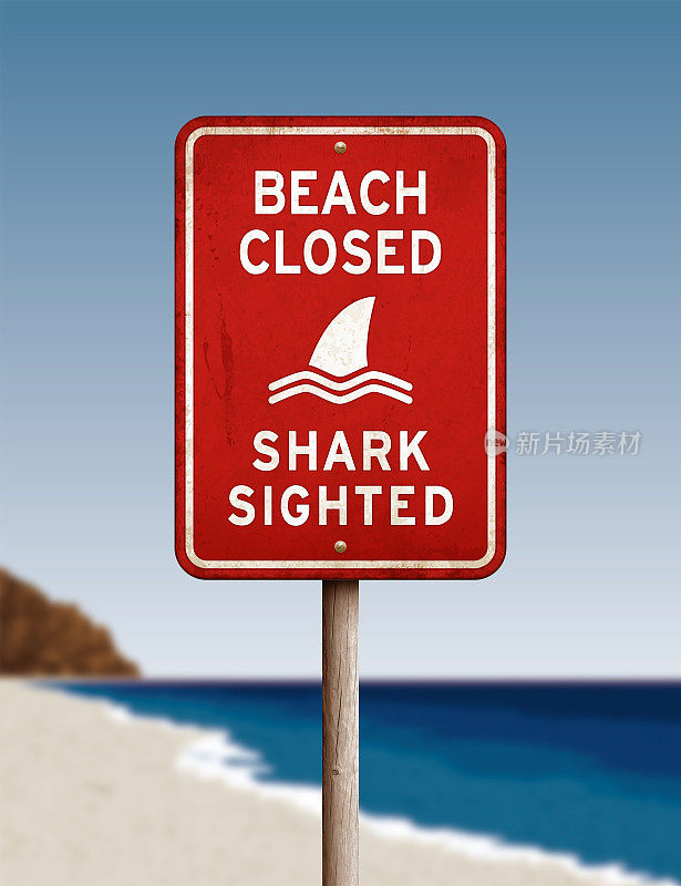 在离焦的海洋背景上，红色的“海滩近-鲨鱼可见”警告标志