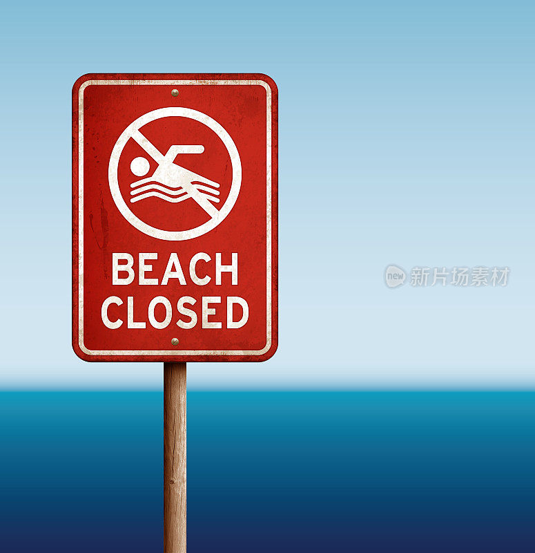 风化的“海滩关闭”警告标志与大海