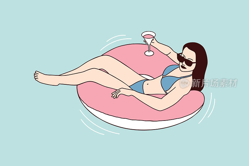 美丽的女人享受夏天的一个充气环池与鸡尾酒