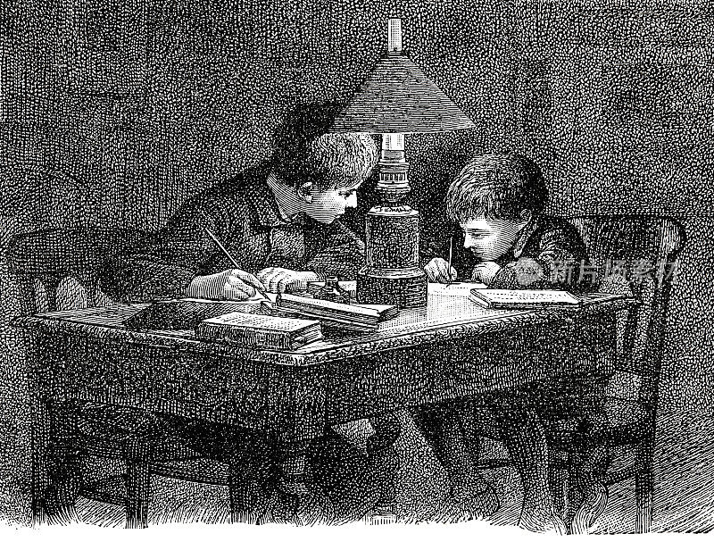 两个男孩借着灯光在书房里写作