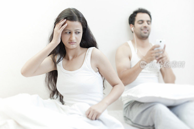 紧张的女人在床上对粗心大意的丈夫生气。