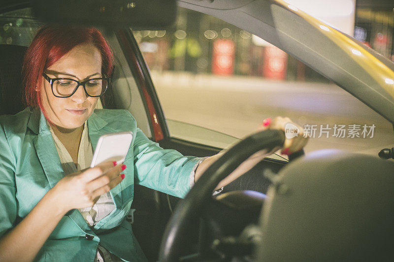 漂亮的年轻女子一边开车一边玩智能手机