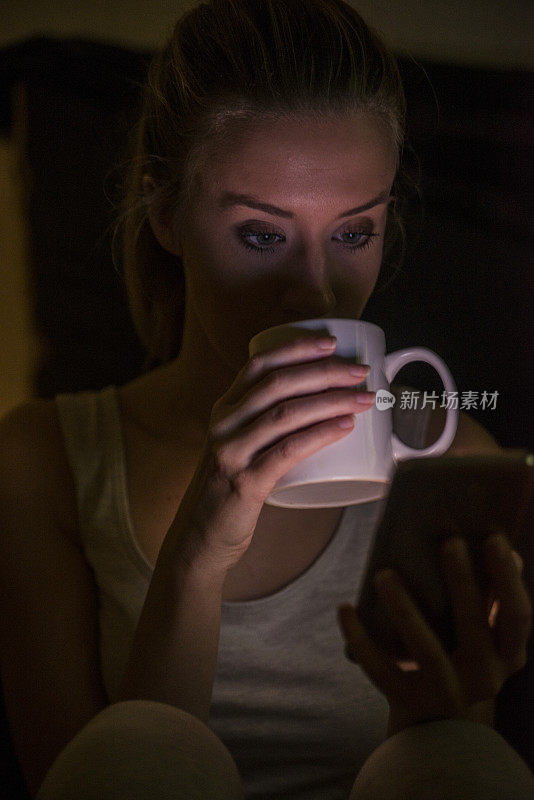 女孩手里拿着智能手机和咖啡杯