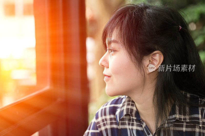 亚洲女性有一个视野看窗外的阳光