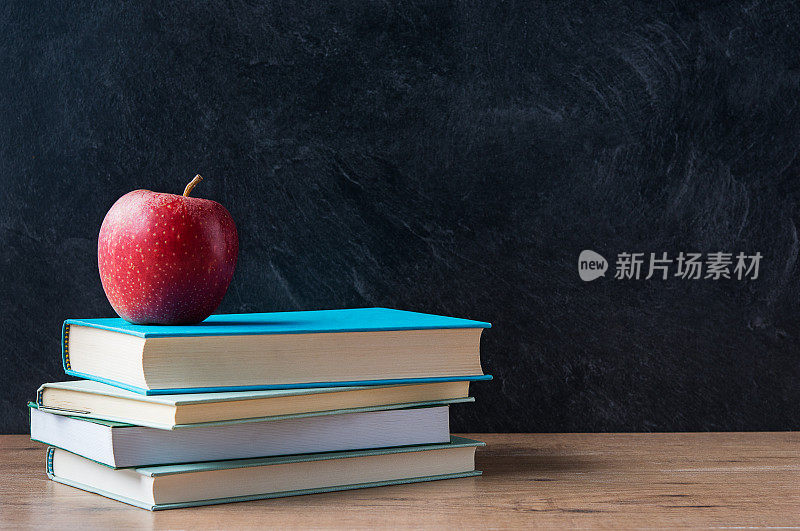 在学校的黑板前堆放在书上的苹果