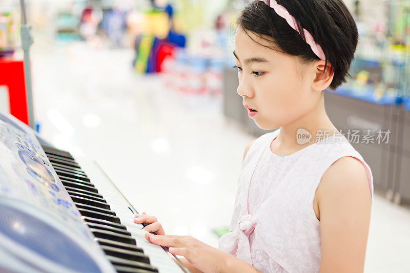 小女孩在音乐店里弹奏电子钢琴