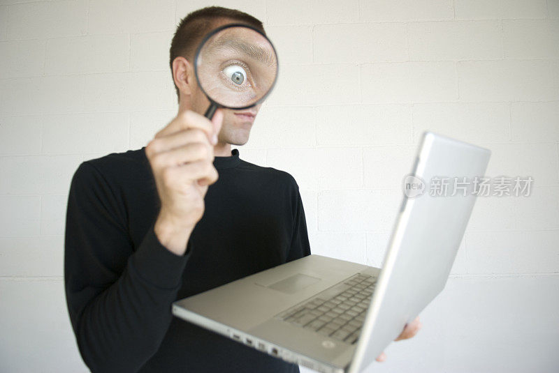 窥探电脑间谍惊讶的眼睛在放大镜与笔记本电脑
