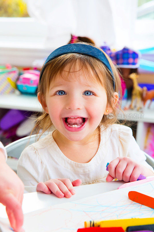 一个微笑的一岁白人女孩在桌子上色