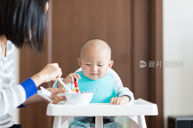 年轻的妈妈在喂她的孩子