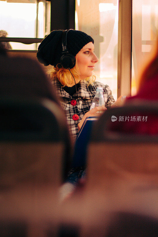 一名年轻女子戴着耳机在公交车上听音乐