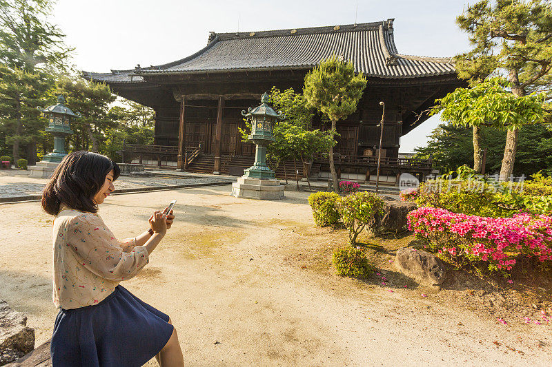 一名日本妇女在一座佛教寺庙里使用手机