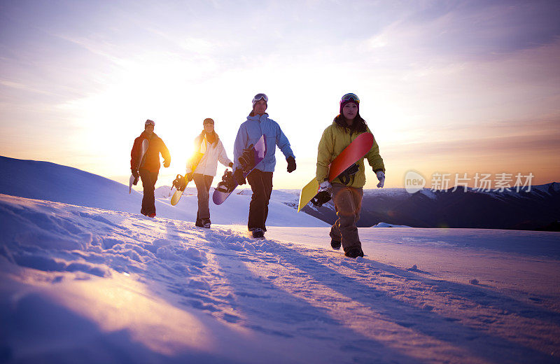 滑雪运动员在雪地上行走，背景是日出