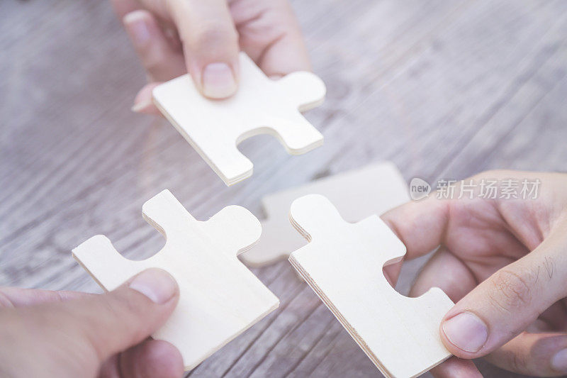 商业伙伴关系或团队合作的概念与一个商业人员呈现一个匹配的拼图块，因为他们合作找到一个答案和解决方案，关闭他们的手。