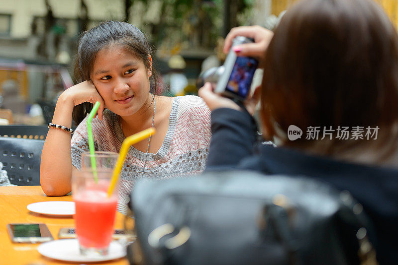 年轻的亚洲女性朋友一起在餐馆里闲逛的照片