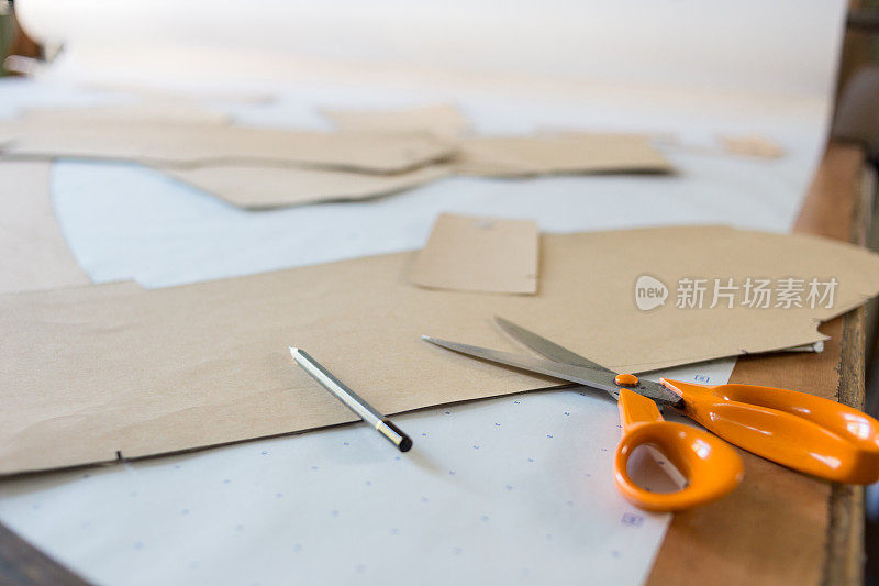 用样板和剪刀拉近裁缝的工作台。