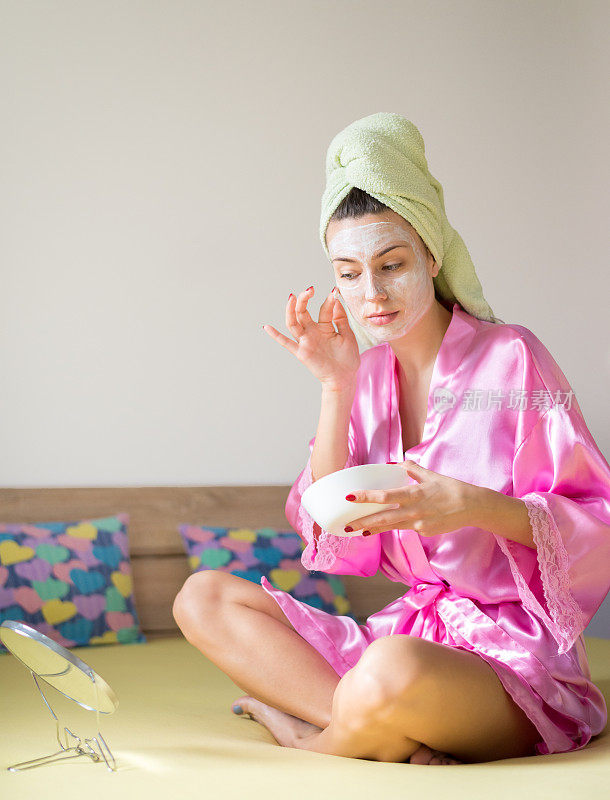 穿着浴袍的年轻女子在家里敷面膜