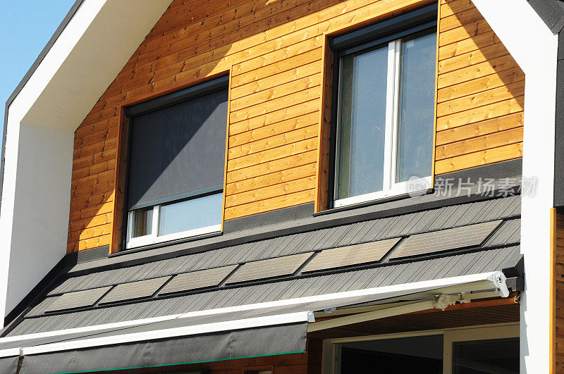 带有太阳能板的房屋百叶窗遮阳外观。新型现代被动式住宅阁楼外立面木墙的窗户，带有百叶窗。