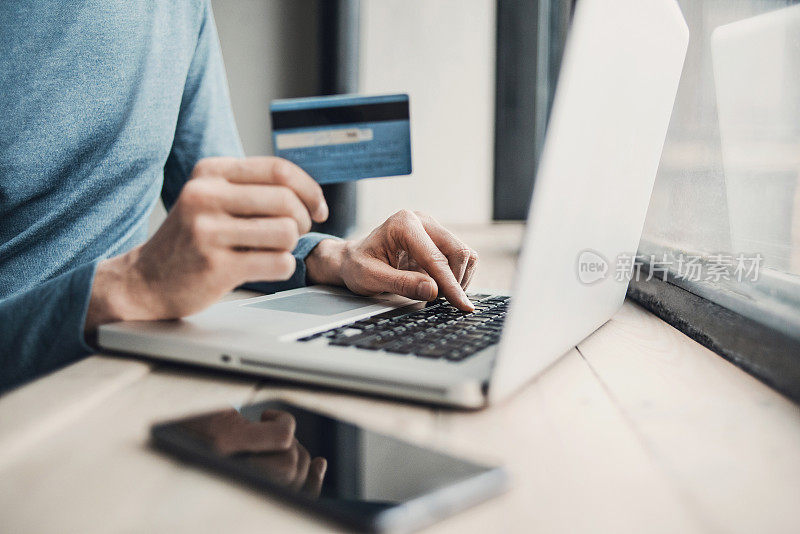 男人用笔记本电脑和信用卡在网上购物