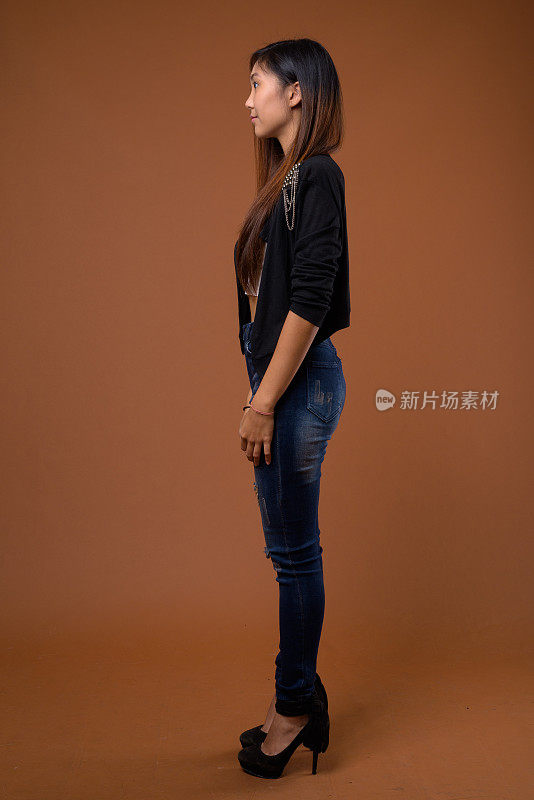 工作室拍摄的年轻美丽的亚洲女子与长直发穿着凉爽的夹克，以颜色的背景