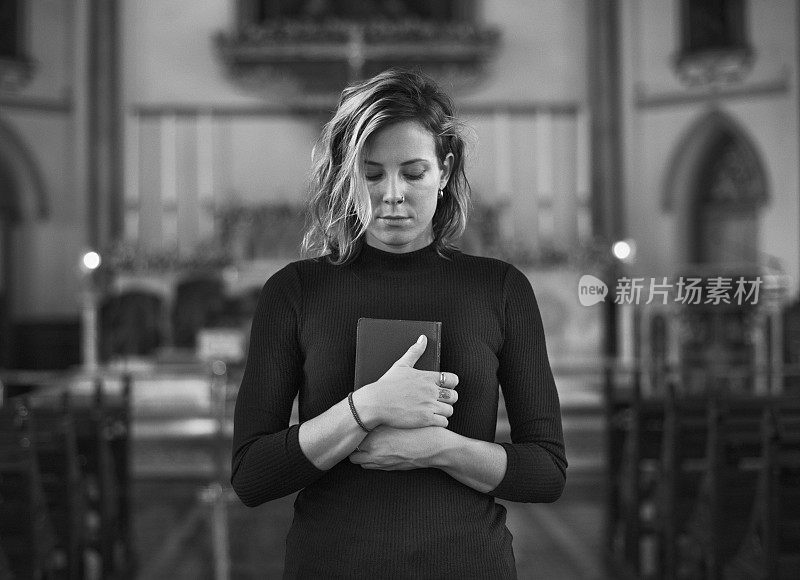 在灰色的教堂里祈祷的女人