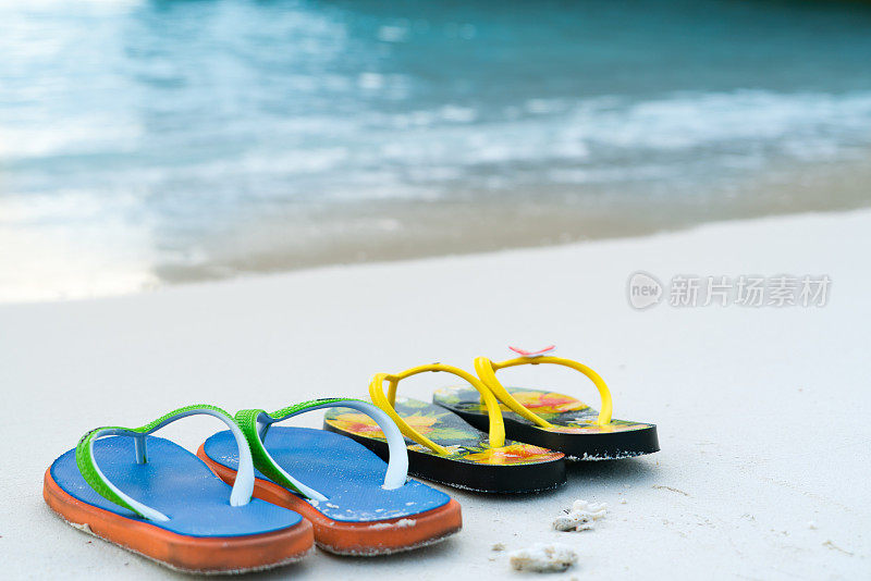 2双拖鞋在白色沙滩上，旅行和度假的时间