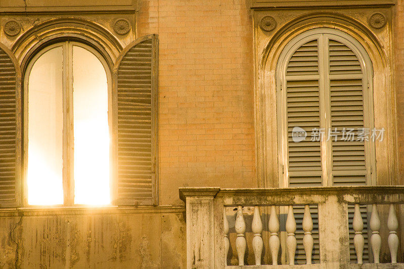 意大利罗马:斑驳的棕色墙壁上的阳光窗，街灯