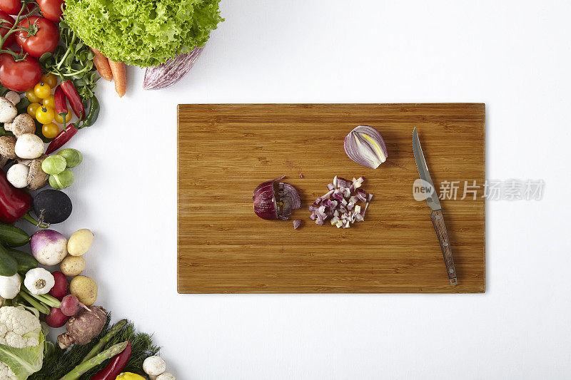 红洋葱用刀切在切菜板上，蔬菜架