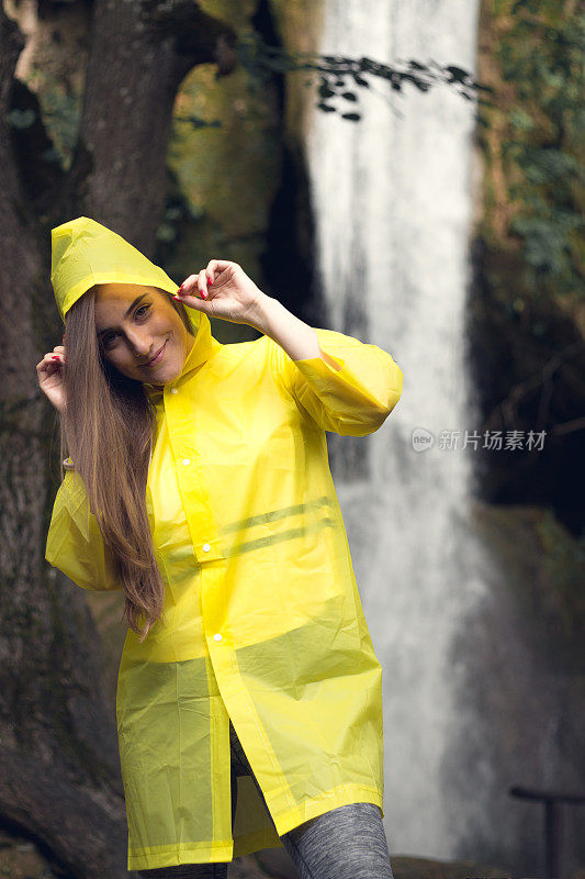 一个穿着黄色雨衣站在瀑布前的女人