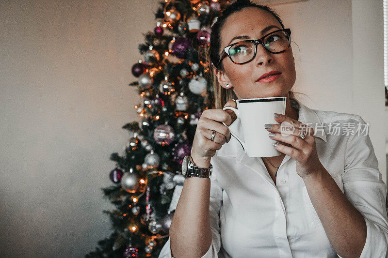 戴眼镜的女人装饰圣诞树，喜欢喝咖啡