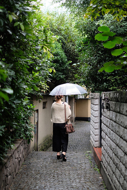 在一个雨天，在东京神乐坂传统老城的小巷里走着的女人的背影