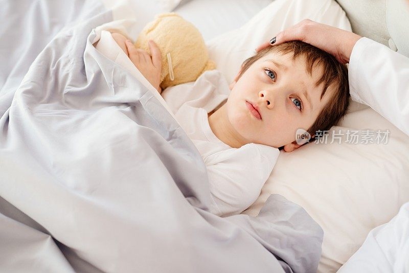 生病的小孩在床上发高烧。