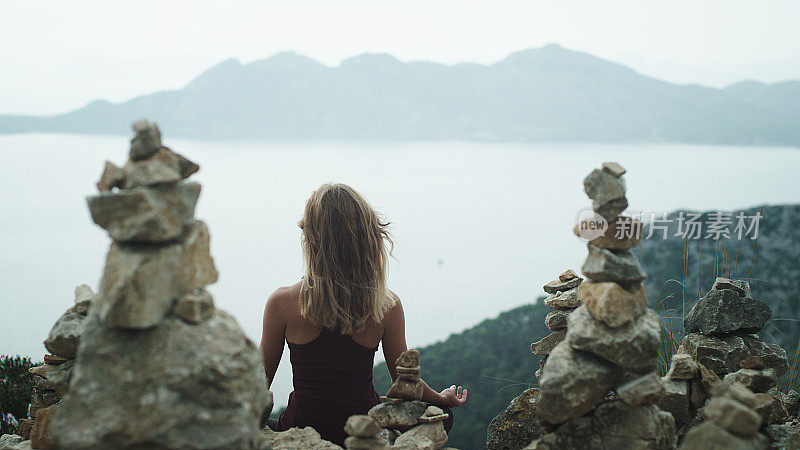 女人冥想。多岩石的海岸线