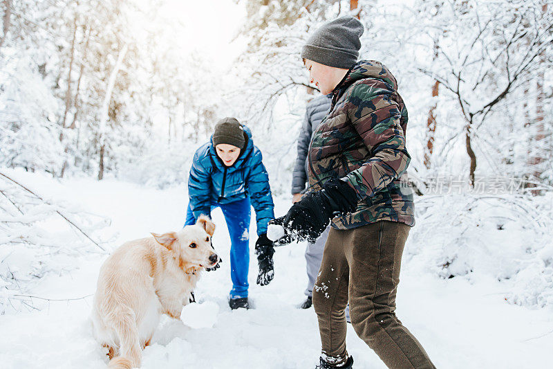 一家人和他们的狗在公园玩雪球