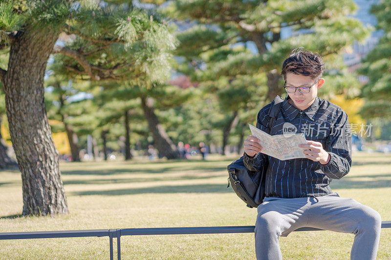 年轻的亚洲男子和日本朋友寻找旅游地点使用手机和花时间在亚洲旅行