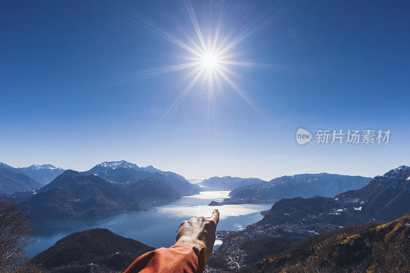 徒步者指指湖面，太阳在晴朗的天空