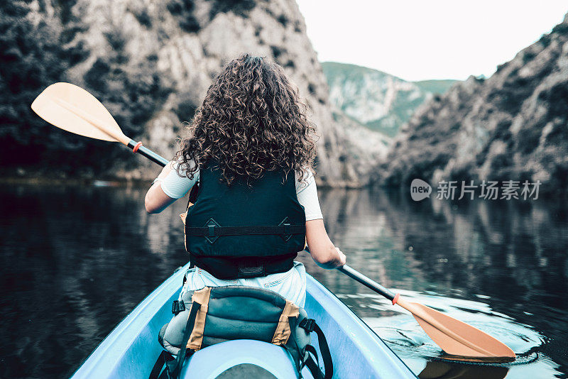 女性水上运动运动员在皮划艇旅行的后视图