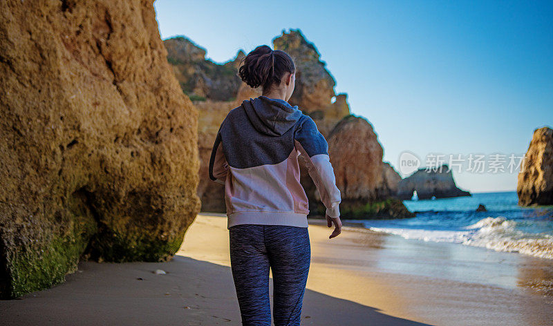 年轻的黑发女性享受她的自由在阿尔沃葡萄牙海滩在夏末的太阳