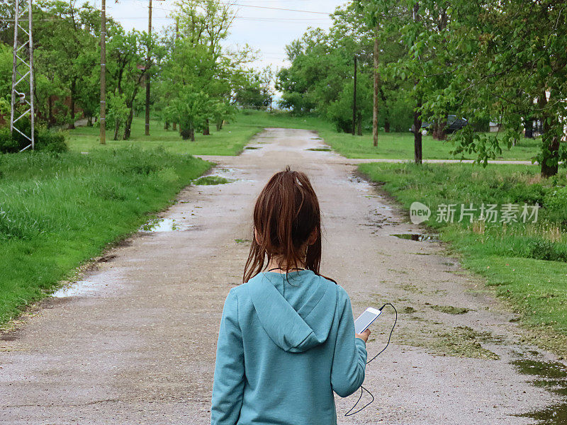 小女孩走在乡村小路上听音乐