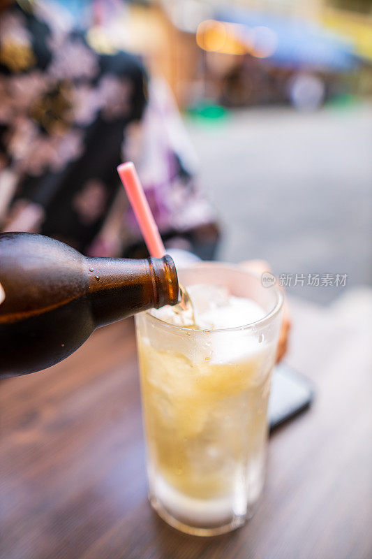 年轻女子在浴场往玻璃杯里倒啤酒