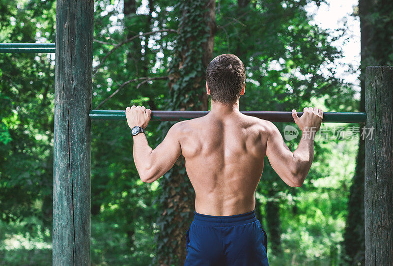 一个肌肉发达的男运动员在公园里锻炼。体操、柔韧性训练、健身锻炼