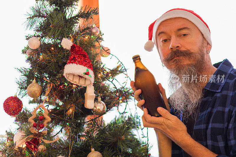 中年男子戴着圣诞帽，用啤酒瓶装饰圣诞树